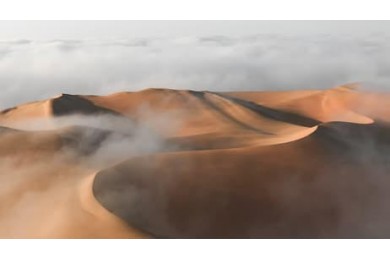 Вид на массивную песчаную дюну, окруженную туманом