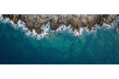 Вид с воздуха на морские волны и скалистый берег