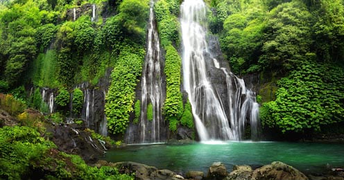 Водопад в тропическом лесу со скалой и прудом