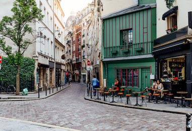 Уютная улочка со столиками кафе и зданием в Париже