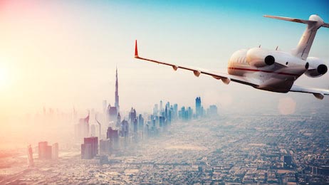 Самолет летящий над городом Дубай в красивом закате
