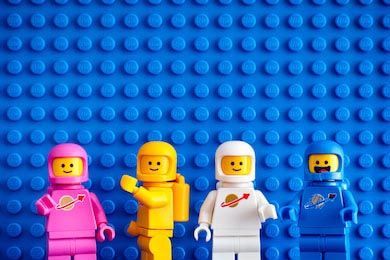 Четыре цветных Лего астронавта на синем фоне