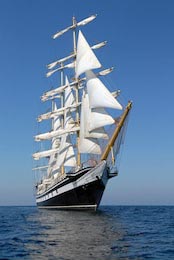 Лодка с белыми парусами на фоне голубого неба