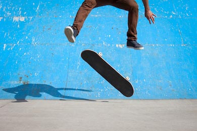 Парень катающийся на скейте на фоне голубой стены