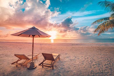 Шезлонги с зонтиком на песчаном пляже на закате