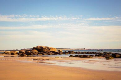 Отлив на пляже в Галиции с камнями на фоне