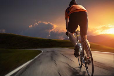 Велосипедист едет по дороге на фоне заката дня