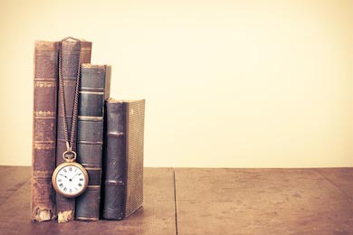 Старинные книги и карманные часы на деревянном столе