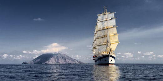 Парусный корабль на фоне большого острова с вулканом