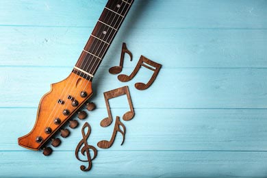 Гитара и музыкальные ноты на цветном деревянном фоне