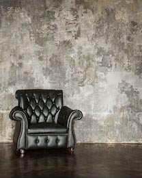 Кресло на фоне серой бетонной стены в стиле лофт