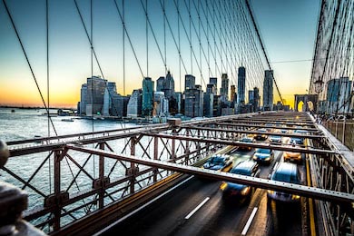 Автомобили несутся на закате на Бруклинский мост